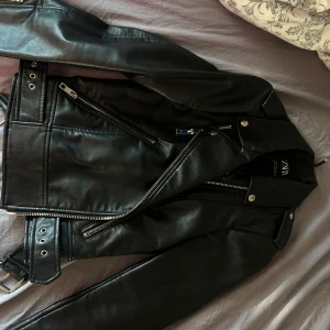 Svart skinnjacka från ZARA med bälte - Säljer min coola skinnjacka från Zara då den aldrig används längre