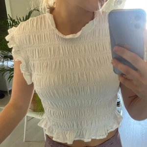 Vit smockad blus med volang från Mango - Hej! Säljer en liten söt blus från Mango i storlek M. Skulle dock säga att den är lite liten i storleken och känns som en XS/S. 