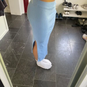 Ljusblå ribbad långkjol från H&M Divided - Snygg ljusblå långkjol från H&M Divided i ribbad stickad kvalitet. Kjolen har en slits på sidan och är gjord av en mjuk blandning av viskos, akryl och polyamid. 