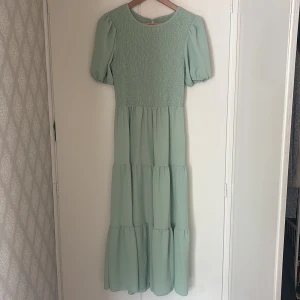 Ljusgrön långklänning med puffärm - Supersöt ljusgrön långklänning med puffiga kortärmar och smockad överdel. Strl S