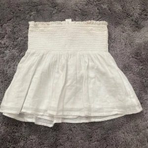 Vit tub topp från Gina  - Supersöt vit tubtopp från Gina funkar som en kjol också säljer den för den är för liten den har en liten fläck där uppe som man ser på bilden men går säkert bort i tvätten annars syns den knappt skriv för mer frågor kan mötas upp 