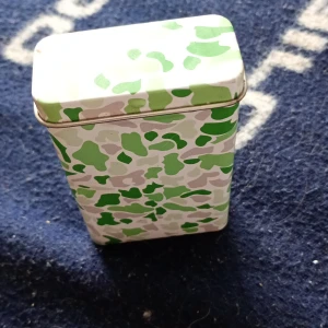 Grön kamouflagemönstrad plånbok - Säljer en plånbok med coolt kamouflagemönster i grönt, vitt och beige. Den har en fyrkantig form och är perfekt för dig som vill sticka ut med accessoarerna. Enkel att ta med i väskan eller fickan.