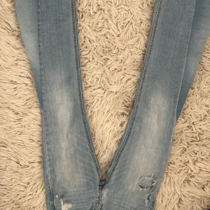 Ljusblå skinny jeans från Hollister - Säljer ett par ljusblå skinny jeans från Hollister med slitna detaljer och snygg tvätt. Jeansen har klassiska bakfickor med dekorativa sömmar och är tillverkade i mjukt denim. Perfekta för en avslappnad och trendig look. SKRIV INAN KÖP