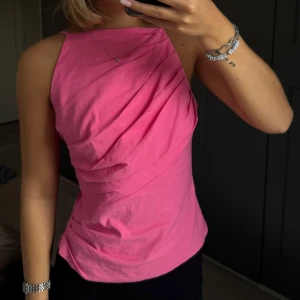 Rosa linnetopp - Super snygg rosa linnetopp med draperad framsida och smala justerbara axelband. Toppen har en rak halsringning och dragkedja i ryggen. Perfekt för dig som vill ha en färgstark och trendig look.