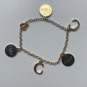 Guldigt armband från Chloé - Snyggt guldigt armband från Chloé med tunna länkar och fem berlocker – tre runda med Chloé Parfum-gravyr och två C-formade berlocker. Perfekt för festligare tillfällen eller till vardags💕. Aldrig använt. Mottagaren står för frakt. Priset är sänkt från 350 till 250kr. Nypris är ca 4500kr så säljer för väldigt bra pris😇