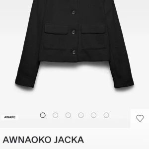 Svart cardigan jacka från Aware - Snygg svart cardigan jacka från Aware med croppad passform, klassisk krage och fyra knappar framtill. Jackan har två fickor med lock och är tillverkad i ett strukturerat, stickat material som ger en cool och trendig look. Perfekt att slänga över en t-shirt eller topp.