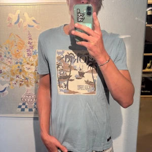 Ljusblå Morris t-shirt med tryck - Fräsch ljusblå t-shirt från Morris med coolt tryck på bröstet. Varan är i fint skick och strl S.