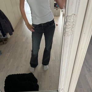 Grå bootcut jeans med paljettdetalj - Säljer ett par grå jeans med bootcut passform och snygg paljettbroderad detalj på bakfickan. De är från Gina Young men sitter endå bra på än 