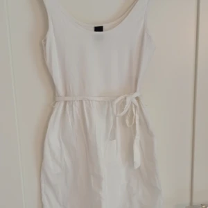 Vit mini bomullsklänning Vila - En super söt vit klänning från Vila💕 Storlek S, har en stretchig överdel och en styvare kjol i bomull. Har fickor och ett avtagbart snöre som går att knyta ii midjan. 
