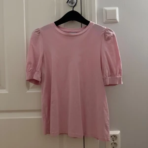Rosa topp med puffärm från Vero Moda - Supersöt ljusrosa topp från Vero Moda Aware, aldrig använd, i ny skick, med puffiga korta ärmar och rund halsringning.