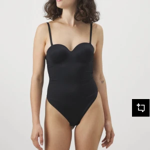 Svart body med tunna axelband - Enkel och stilren svart body med tunna justerbara axelband och lätt vadderade kupor. Snygg, figurnära passform och hög benskärning som ger en modern look. Storlek 75a 