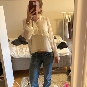 Vit prickig blus - Tröjan är i 158, är som xs eller s. Supersöt vit blus från Lindex med diskreta prickar och volangdetalj framtill. Långärmad modell i lätt och luftig polyester, perfekt för vår och sommar. Blusen har rund halsringning och knäppning bak i nacken. Passar till både jeans och kjol.