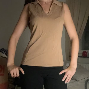 Beige ärmlös linnetopp med krage - Säljer en stilren beige linnetopp med klassisk krage och v-ringning. Toppen är ärmlös och har en enkel, clean look som passar perfekt till jeans eller kjol. Materialet känns mjukt och lätt, perfekt för varmare dagar.