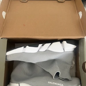 Grå Balenciaga Speed sneakers - Säljer ett par grå Balenciaga Speed sneakers med vit och svart chunky sula. Skorna har en strumpliknande passform i stickad syntet och Balenciaga-logga på sidan. Perfekta för dig som gillar futuristisk och clean stil. Storlek 43 men stora i storlek
