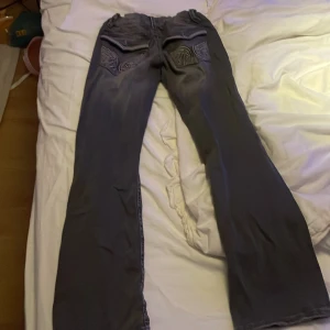 Grå jeans med broderade fickor Gina Tricot - Snygga grå jeans från Gina Tricot med broderade detaljer på bakfickorna. Byxorna har raka ben och normal passform. Perfekta för dig som vill ha ett par unika jeans med coola detaljer.