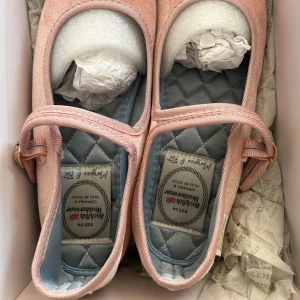 Rosa ballerinaskor från Rockfish Weatherwear (UK5, 245)  - Söta ballerinaskor i ljusrosa sammet från Rockfish Weatherwear. Skorna har en klassisk rund tå, platt svart sula och ett smalt band över foten med guldfärgat spänne. Insidan är quiltad i ljusblått för extra komfort. Perfekta för en chic och feminin look. Jag använde bara två gånger då finns det fläckar och köper billigare än! Det går lätt att ta bort dammet. Skornas storlek är 245 (UK5) men min är 240. 