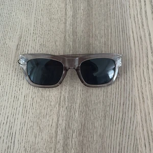 Gråa  transparenta solglasögon - Snygga solglasögon med transparent brun båge och svarta glas. Rektangulär form som ger en cool vibe och passar till de flesta outfits. Perfekta för att lyfta din stil under soliga dagar.
