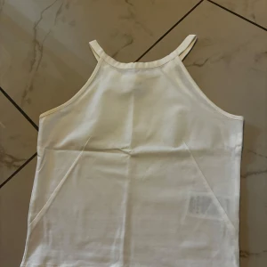 Ny vit linnetopp från Gina Tricot XS - Snygg vit linnetopp från Gina Tricot i storlek XS. Toppen har smala axelband och rak passform, perfekt till varma dagar. Ej använt. 