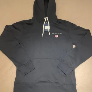 Oanvänd Gant medium shield hoodie - Oanvänd Gant medium shield hoodie. Storlek M. Nypris ca 1000kr. Pris 700kr eller bud.