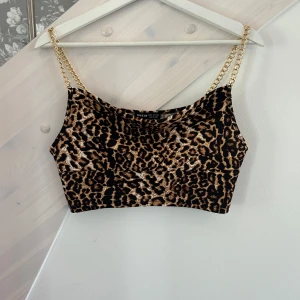 Leopardmönstrad croppad topp Shein - Snygg croppad topp från Shein med leopardmönster och tunna kedjeaxelband i guld. Toppen har en tight passform och är perfekt för dig som vill sticka ut. Materialet är mjukt och följsamt, och färgerna går i brunt, svart och beige.