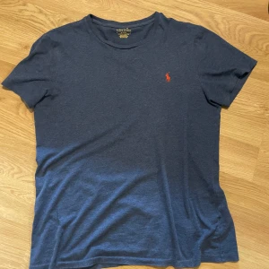 Blå t-shirt från Ralph Lauren - Snygg marinblå t-shirt från Ralph Lauren. Tröjan är i mycket bra skick och det finns inga defekter på den. Skriv om ni har frågor.