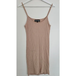 Beige ribbad klänning från Stay - Beige ribbad klänning från /STAY – stl S Klänningen har smala axelband, figurnära passform och är gjord i ett stretchigt material som sitter fint på kroppen. 