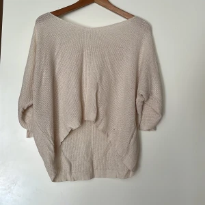 Beige stickad oversized tröja - Säljer en beige stickad tröja med oversized passform och trekvartsärmar. Tröjan har en bred, rund halsringning och är tillverkad i ett mjukt, grovstickat material. Perfekt för lager-på-lager och chill dagar. 