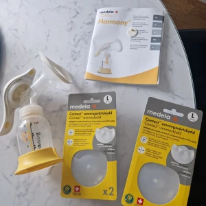 Bröstpump Harmony och amningsvårtskydd -medela - Säljer bröstpump som är anvönd fårtal gånger ingår även en manual för Medela Harmony bröstpump, perfekt för dig som vill ha en smidig och portabel lösning för amning. Innehåller även 2 packet med amningsvårtskydd i storlek L. Passar föräldrar som söker praktiska hjälpmedel vid amning.