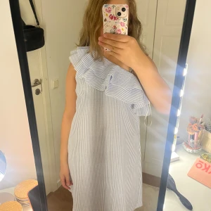 Randig omlottklänning med volang - Säljer denna blå/vit randiga omlott klänning från Vero Moda då den inte kommer till användning för mig!💓 fint skick och endast använd en gång❤️Tvättas innan jag postar!💓