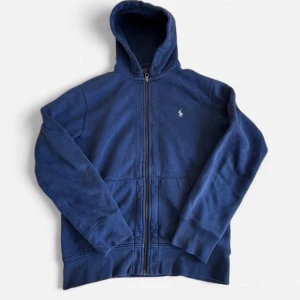 Blå zip hoodie från Polo Ralph Lauren - Mörkblå Polo Ralph Lauren-hoodie, dom två defekta områden visas på bilderna ovan.