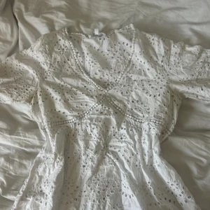 Vit blus - Superfin vit blus från Vintage Stories, Kappahl med broderade detaljer och v-ringning. Blusen har korta ärmar med vågig kant. Snyggt hålmönster över hela plagget ger en romantisk vibe.