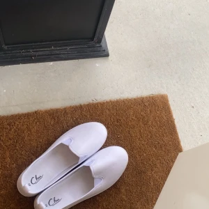 Vita tyg skor från din Sko - Säljer dessa super snygga tygskorna som är den perfekta blandningen mellan ballerina och sneaker. Skorna är köpta på din sko och är märket Clou. Endast använda en gång! Skriv om frågor eller fler bilder!💕 