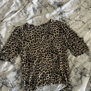 Leopardmönstrad topp från Lager 157 - Cool topp från Lager 157 i leopardmönster med beige och svarta toner. Modellen har halvlånga ärmar och en rak passform som sitter snyggt. 