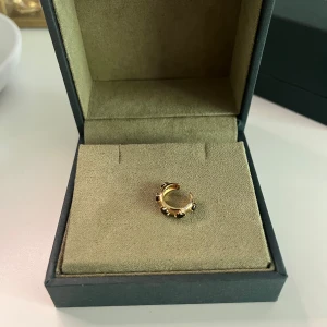 Maria Nilsdotter guld ear cuff - Cool ear cuff i guld med svarta sten detaljer från Maria Nilsdotter. Använd fåtal gånger. Fin detalj som ger ett cool intryck.