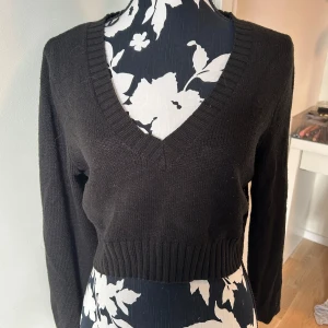 Svart croppad stickad tröja L - Svart croppad stickad tröja från Gina Tricot i storlek L. Tröjan har djup v-ringning. Väldigt bekväm och sparsamt använd, säljer då den är för kort på mig.
