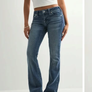 Blå bootcut jeans från True Religion - Snygga blå jeans från True Religion med klassisk bootcut-passform och ikoniska broderade bakfickor. Jeansen har normal midja och är tillverkade i mjukt denimtyg som ger en skön känsla. Perfekta för dig som gillar en tidlös och avslappnad stil. Original pris 1200kr, pris kan diskuteras 😊