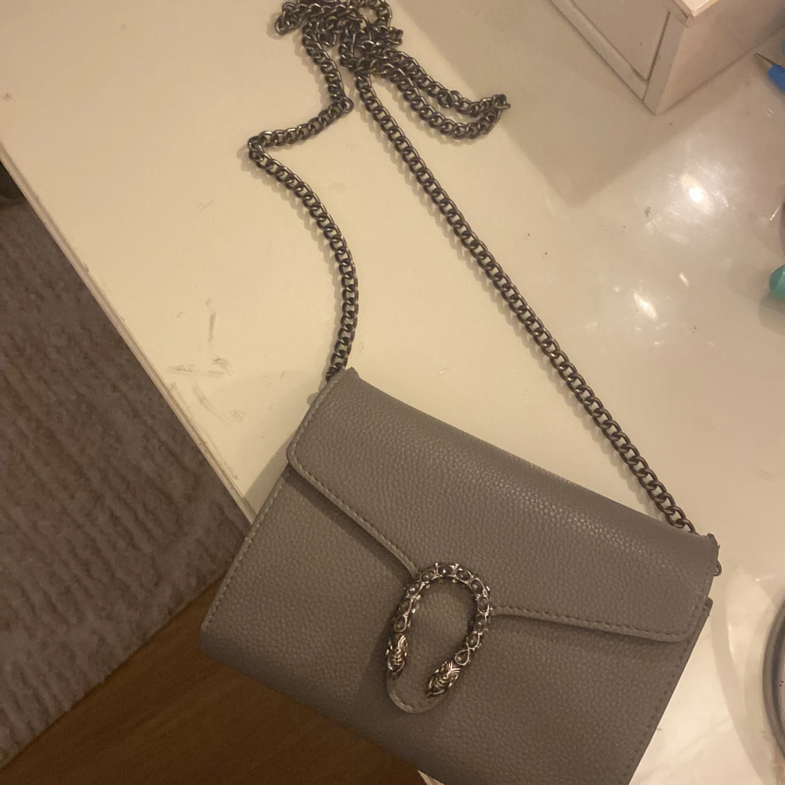 Grå axelväska med kedja och detaljspänne