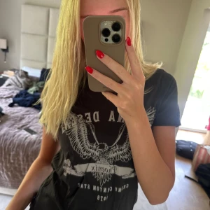 Svart Arizona Desert t-shirt Gina Tricot - Svart t-shirt från Gina Tricot med tryck av en örn och texten 'Arizona Desert Phoenix Grand Canyon State 1978' på framsidan. Klassisk rund hals och korta ärmar. Skön bomullskvalitet och normal passform. Perfekt för en cool och avslappnad look.