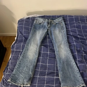 Blå bootcut jeans med slitningar - Snygga ljusblå jeans med bootcut passform och slitna detaljer vid bensluten. Klassisk femficksmodell i jeansmaterial med en cool tvättad look. Perfekta för dig som gillar retrovibbar och vill ha ett par jeans som sticker ut.