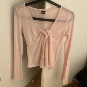 Ljusrosa långärmad topp Gina Tricot -  ljusrosa långärmad topp från Gina Tricot med v-ringning och knyt framtill. Tunn och lätt i materialet, i size s