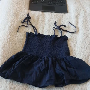 Mörkblå croppad linnetopp med knytband💙 - Säljer en mörkblå croppad linnetopp med smockad överdel och knytbara axelband💞Toppen har en volang nertill och är perfekt för varma dagar☀️🍹 Kan också användas som kjol om man stoppar in axelbanden