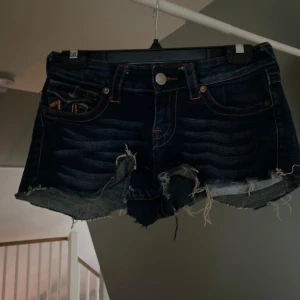Mörkblå jeansshorts från True Religion - Säljer ett par mörkblå jeansshorts från True Religion. Klippte dem hemma själv därför man inte hittar dem på hemsidan. Väldigt bra skick, inga fläckar eller liknande. Står att storleken är 27 i dem men passar på mig som har st xs-s
