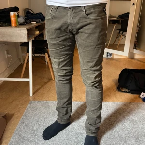 Replay Anbass olivgröna jeans - Säljer ett par olivgröna Replay Anbass jeans med klassisk femficksdesign och normal passform. Byxorna har dragkedjegylf och är tillverkade i ett mjukt bomullsmaterial med lite stretch. Perfekta för dig som gillar stilrena och bekväma jeans.