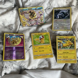 Pokémonkort: Greninja BREAK, Lugia, Ash's Pikachu, Pikachu, Doublade - Samling av fem Pokémonkort, inklusive holografiska och specialkort som Greninja BREAK och Lugia. Perfekt för samlare och fans av Pokémonvärlden. Korten har färgstarka motiv och passar både nya och erfarna samlare. Helt okej skick men är finna