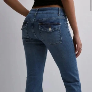 Low waist  bootcut jeans  - Snygga blå jeans med bootcut passform och klassiska fickor bak med lock och knapp. Jeansen har låg midja och stängs med dragkedja och knapp framtill. De är lite uppsydda och passar någon som är ca 165 cm.