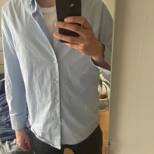 Ljusblå skjorta - Säljer en stilren ljusblå skjorta med klassisk krage och knäppning framtill. Bra skick inga defekter