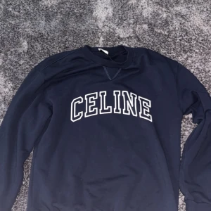 Mörkblå sweatshirt från Celine - nypris 9500kr. Säljer en mörkblå sweatshirt från Celine med vit logga framtill. Tröjan har rund halsringning och långa ärmar. Perfekt för en stilren och avslappnad look.