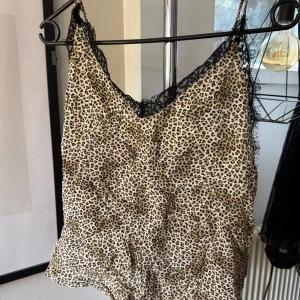 Leopardmönstrad Linnetopp från Gina Tricot  - Säljer en snygg leopardmönstrad linnetopp från Gina Tricot med svarta spetsdetaljer längs urringningen och axelbanden. Toppen har tunn, luftig känsla och smala axelband. Den är i storlek 36 och är lite sliten i spetsen 