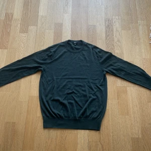 Mörkgrön stickad tröja från Uniqlo - Säljer en stilren mörkgrön stickad tröja från Uniqlo i storlek S. Tröjan har rund halsringning och långa ärmar, perfekt för lager-på-lager eller som den är. Enkel och klassisk design som passar till mycket.