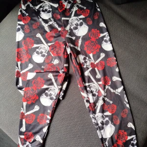 Leggings - Rockiga leggings med rosor och dödskallar i lite silkigt material. Hittar ingen storlekslapp men uppskattar att dom är en stl S. Mycket fint skick.